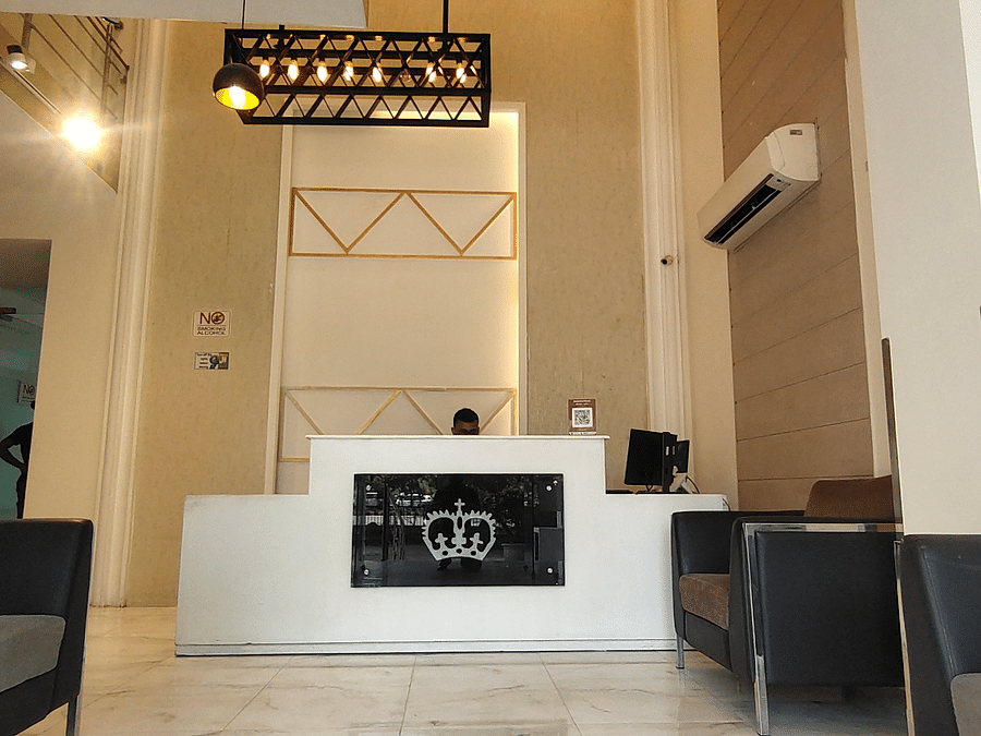 Interior view of a reception area featuring a desk, a decorative light fixture, and seating on either side - Asian Suites Cyber Park, Gurgaon.  