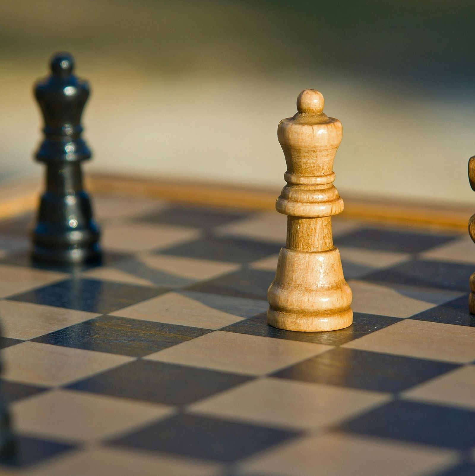 A wooden chess board with four chess pieces.