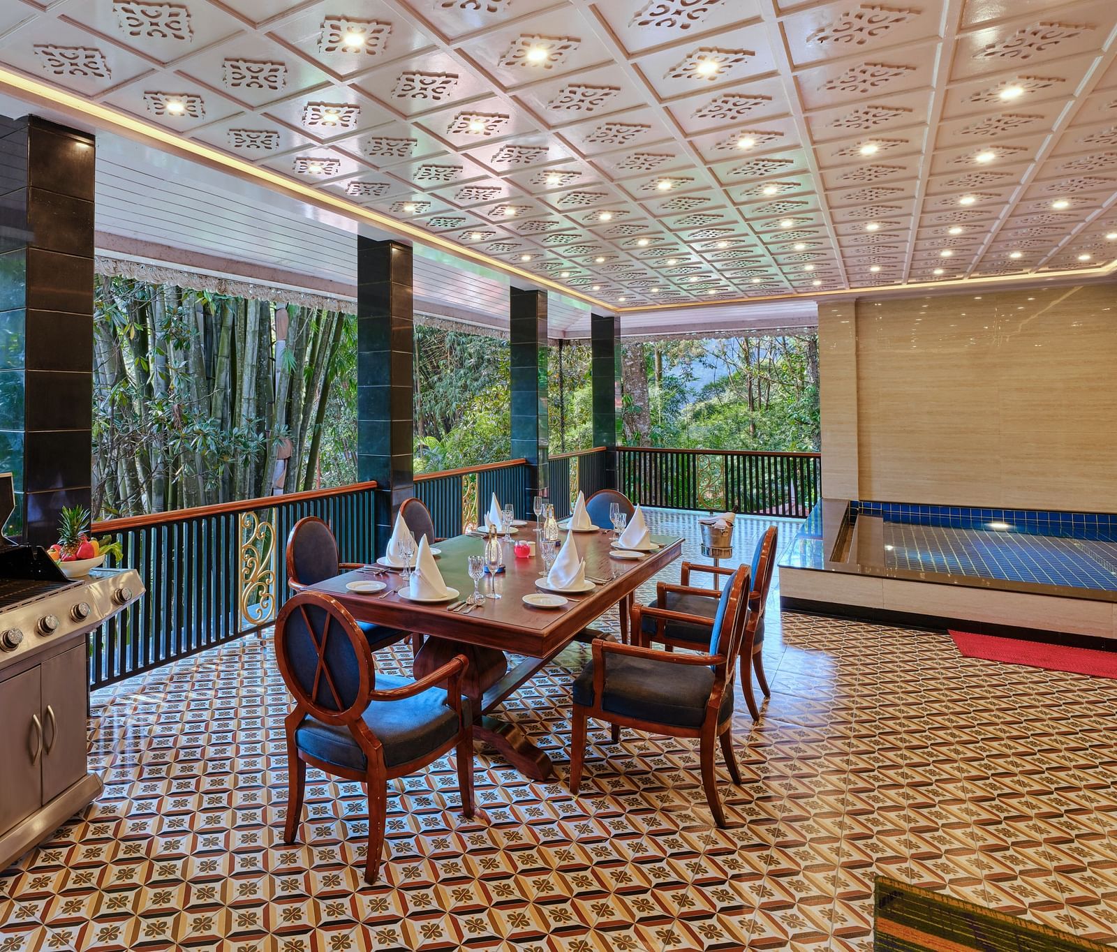 Regent villa outdoor dining area with a barbecue grill, table, chairs and a swimming pool.