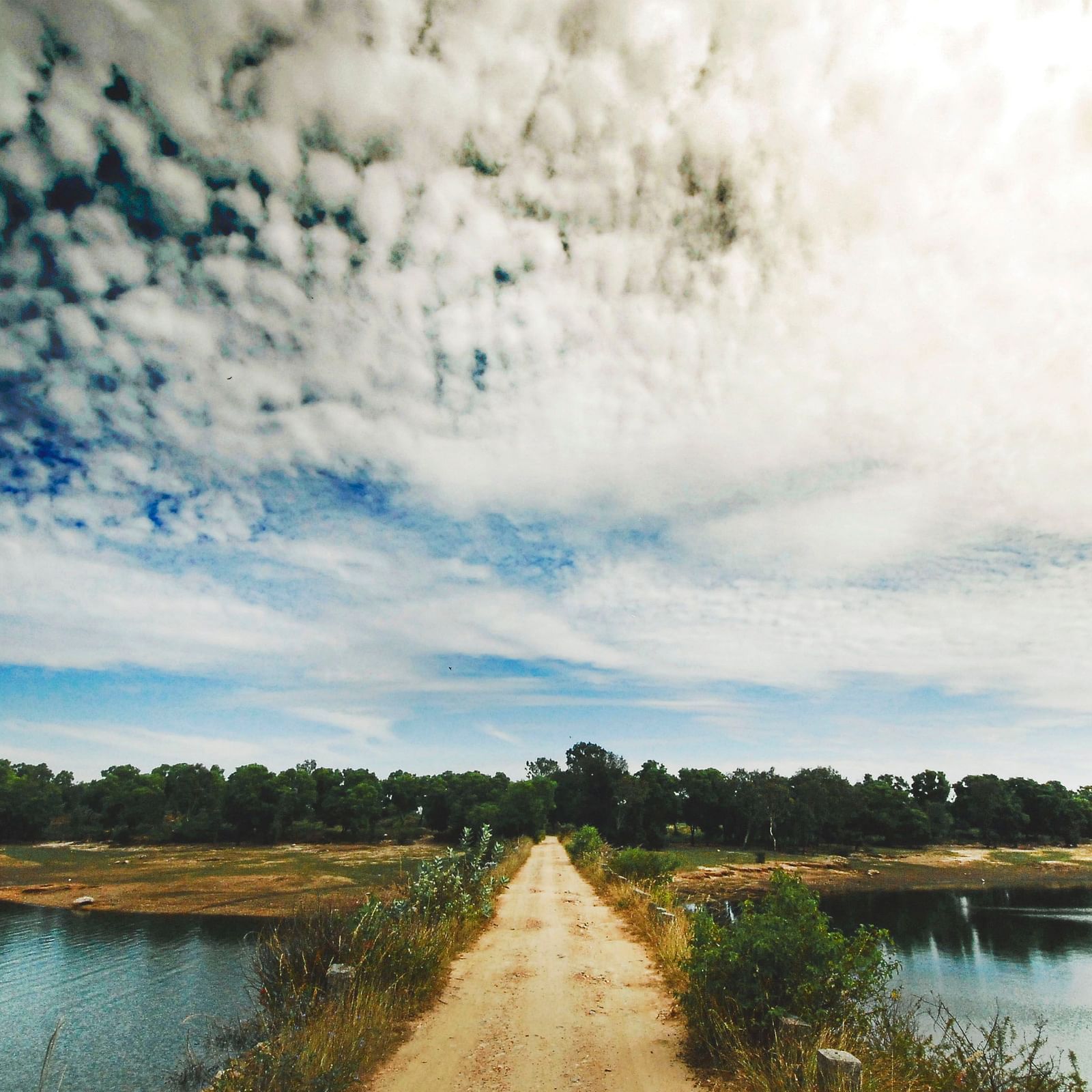 image of a kacha road in the middle with a bright backdrop with clouds