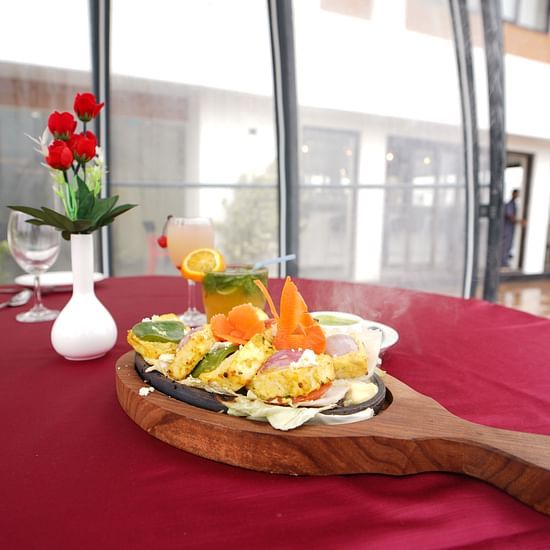 a food item served in a unique tray with roses kept in a small vase on the table