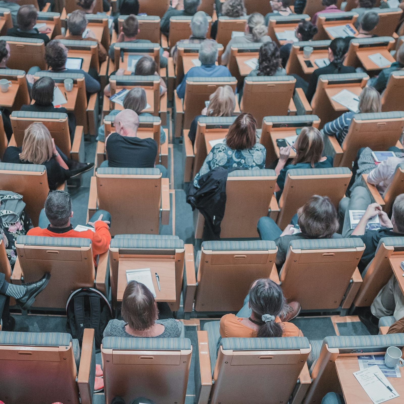 An aerial view of many people in theatre style seating listening to a meeting