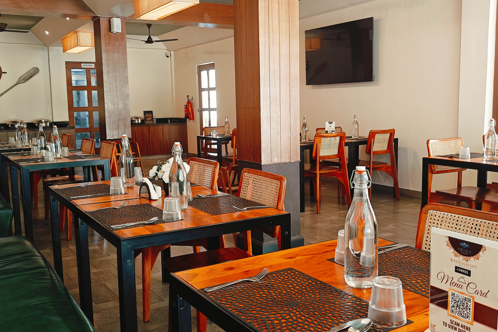 An indoor dining area at Arina Island Resort featuring neatly arranged wooden tables, cushioned seating, and nautical-themed wall decor