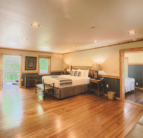 a bedroom with wooden flooring featuring a double bed in the middle - Historic Tapoco Lodge