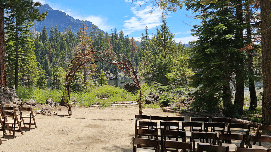 An outdoor ceremony setup at Kit Carson Lodge with rows of wooden chairs overlooking a mountain and forest backdrop