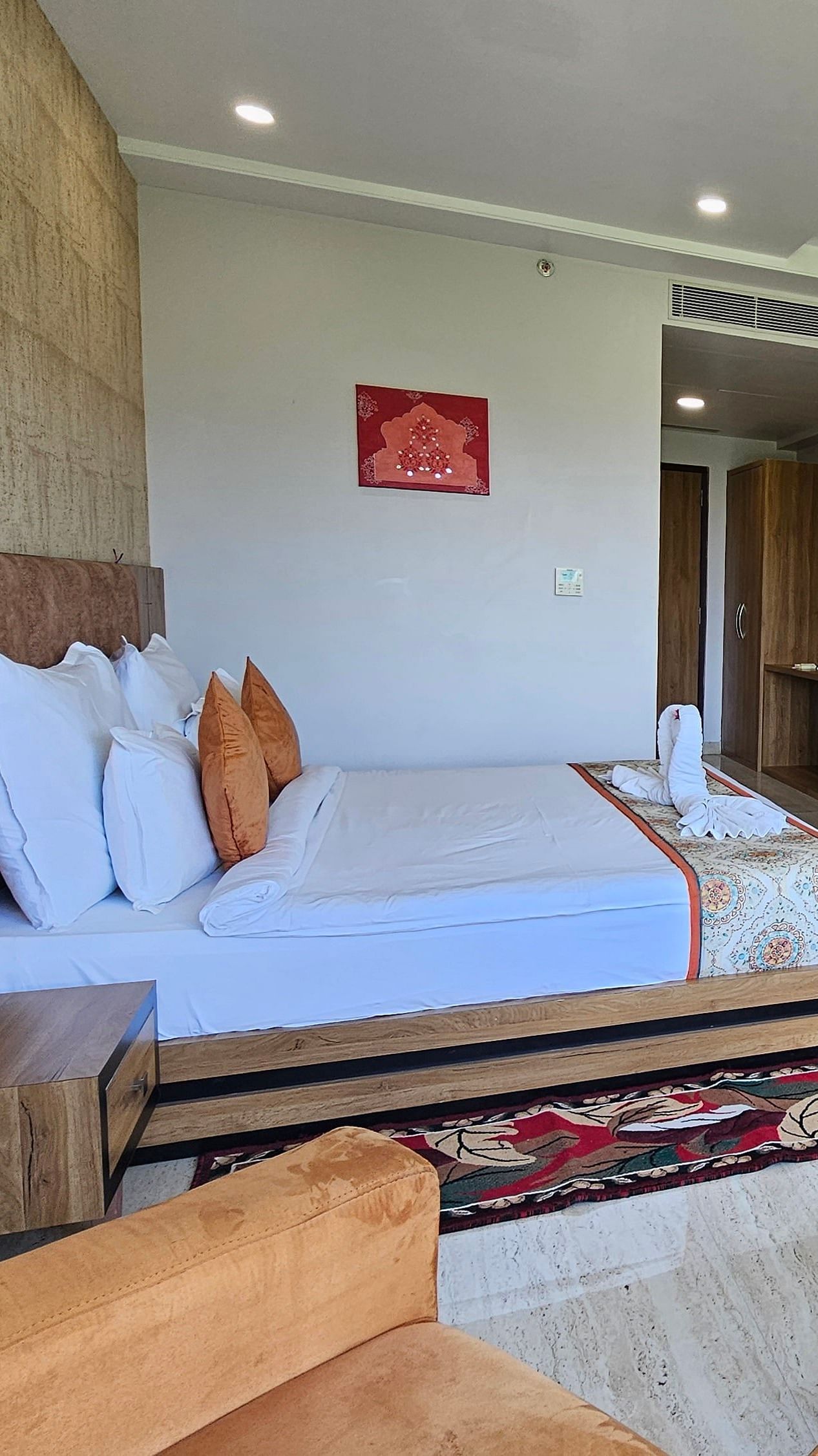 An wider shot of a room at Bamboo Saa Mulberry Resort, with a bed, seating area, a television, and a decorative rug.