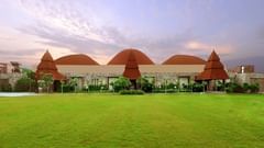 Stone facade cottages and domed architecture set against landscaped lawns at The Ananta Udaipur