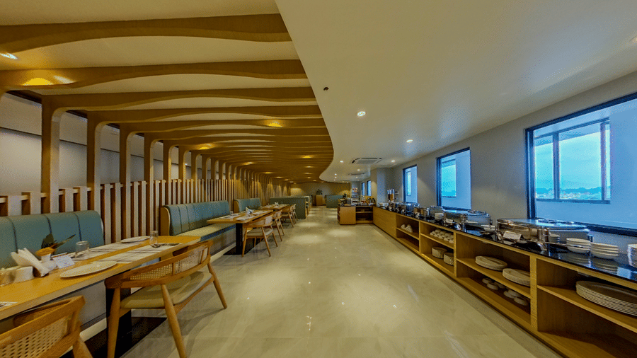 A spacious dining area with neatly arranged tables, buffet counter, wooden accents, and large windows | Lords CBC Plaza, Chitwan
