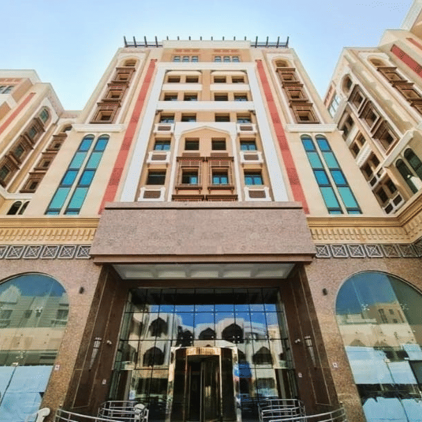 Facade view of La Maison Hotel, Doha from below with blue sky in the background.