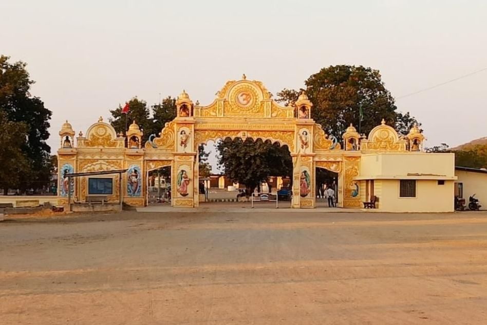 Grand ornamental entrance gate of Satadhar, adorned with intricate carvings amidst serene surroundings.