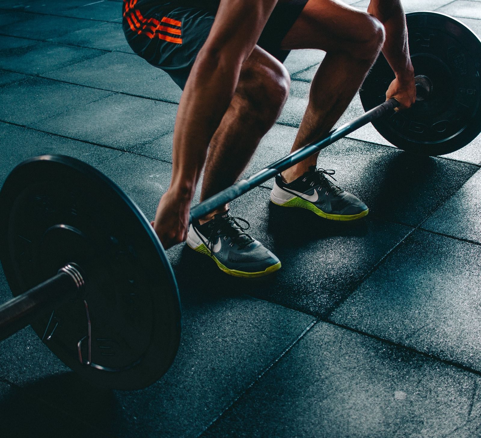 A person performing a deadlift exercise with a barbell on a gym floor