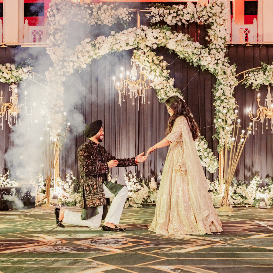 Jaswinder and Ritika performing wedding ritual under floral arch at Umaid Palace.