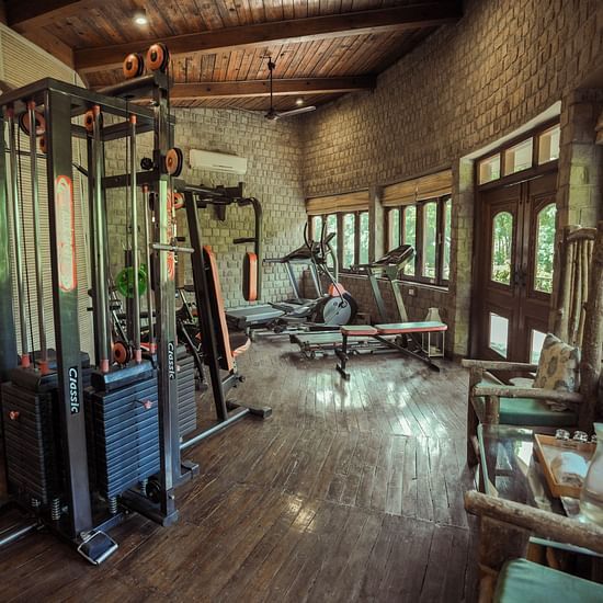 A gym with exercise equipment and large windows, interior setting.