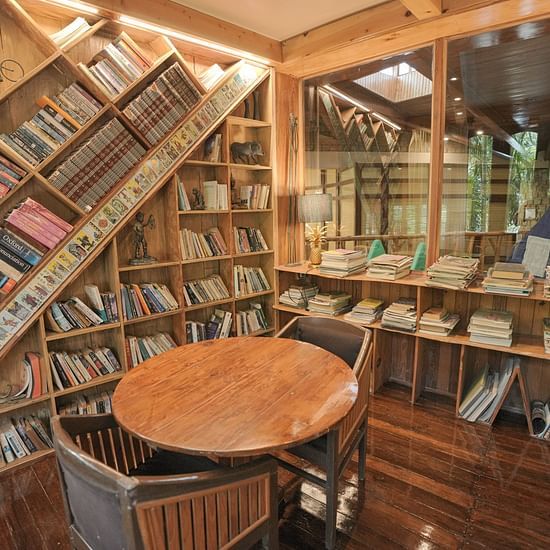 A room filled with bookshelves, a round wooden table, and warm lighting.