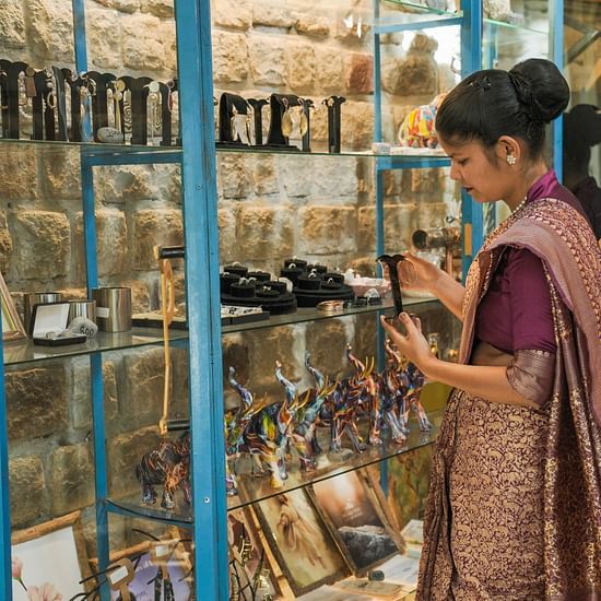 A person in a patterned garment looking at items on a shelf, possibly in a shop or display.