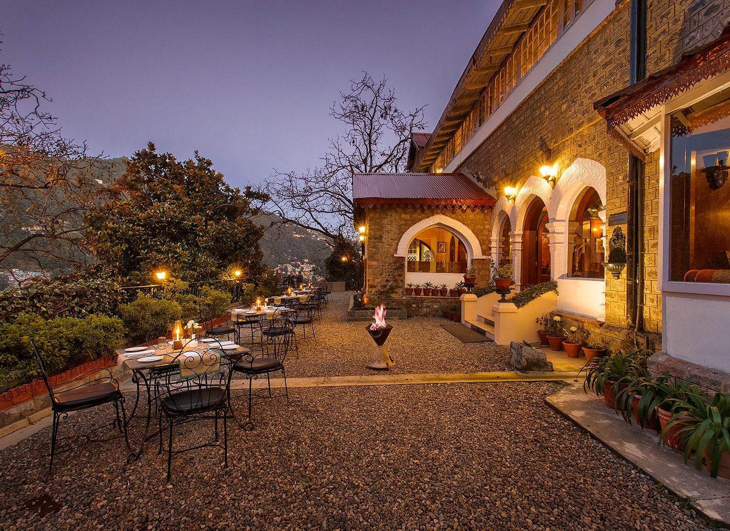 An image of naini retreat, nainital, with a scenic view of  building with a stone exterior and arched doorways. The building is illuminated by warm lights, creating a cozy atmosphere. 