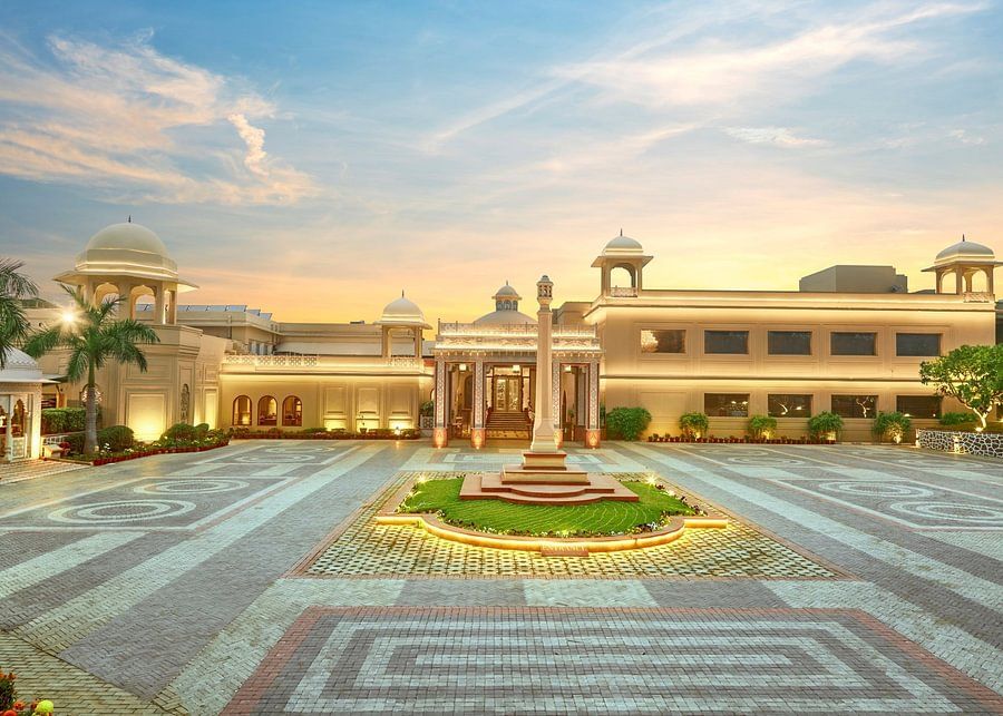 Grand view of a palatial building with domes and a large courtyard at sunset - Heritage Village Resorts & Spa.