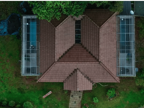 An aerial view of a cottage with a unique M-shaped roof, surrounded by lush greenery at Abad Brookside Lakkidi, Wayanad.