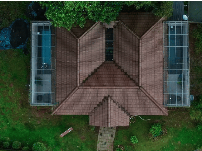 An aerial view of a cottage with a unique M-shaped roof, surrounded by lush greenery at Abad Brookside Lakkidi, Wayanad.