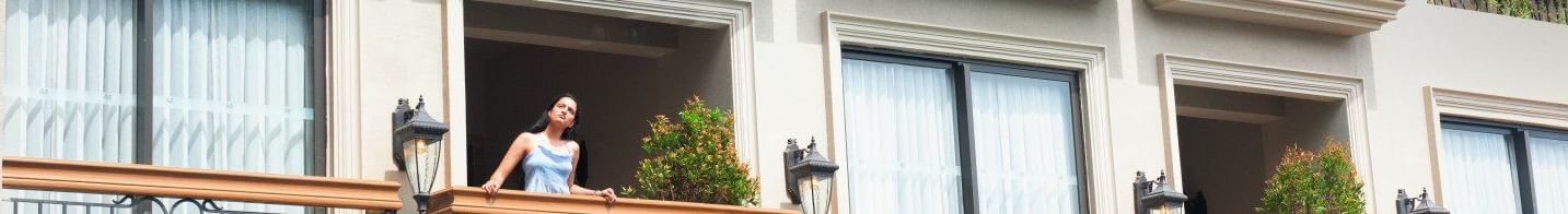 A woman standing in the balcony looking at the surrounding as she leans against the railing at The Evren, Vagator.