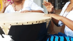 Two women playing a drum