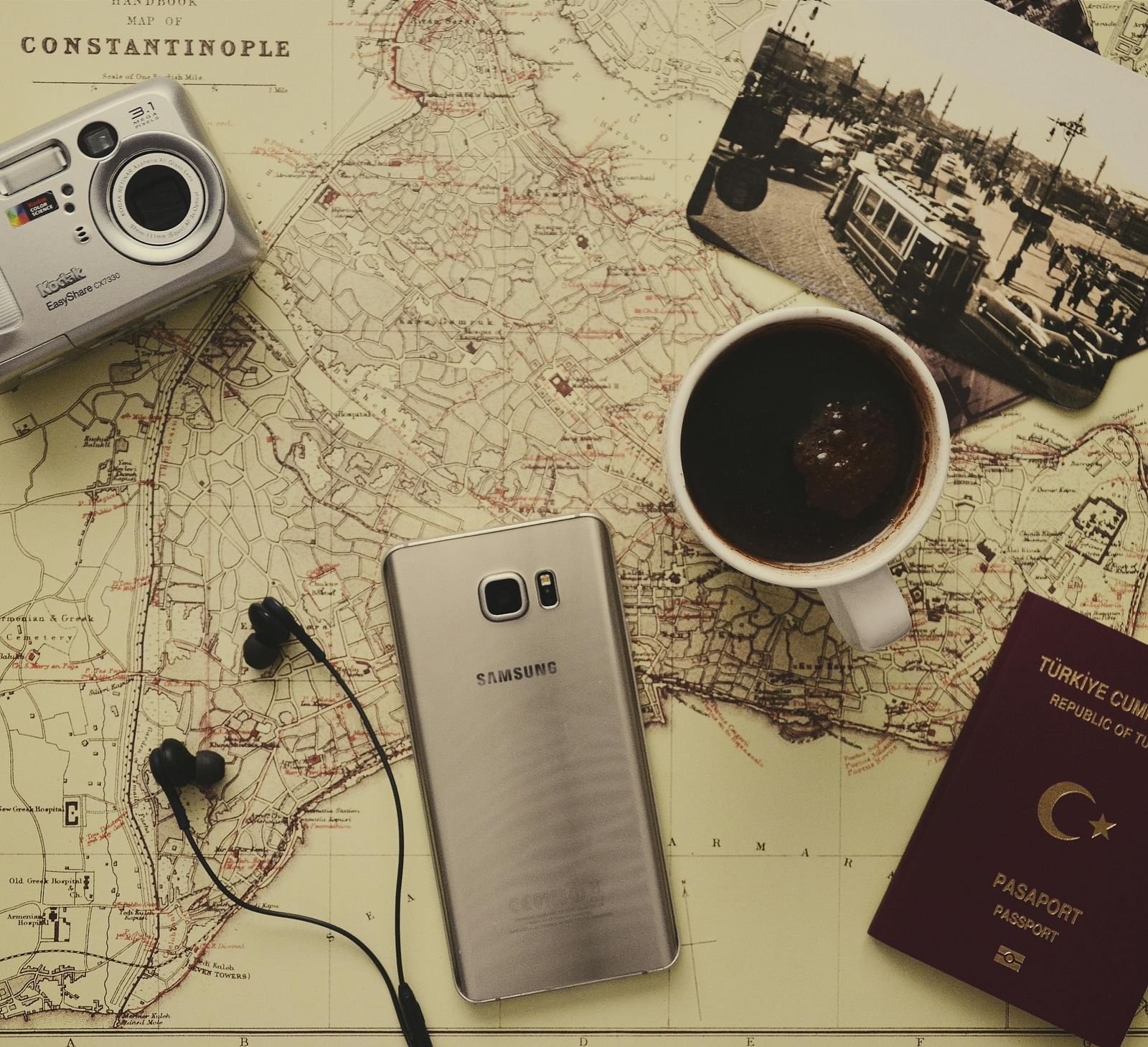An image of a table laid our with a map, camera, phone, passport, photograph, and coffee