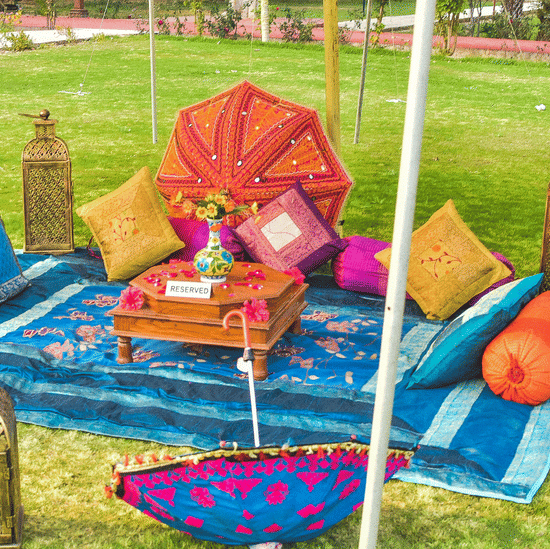 Colourful haldi or mehendi setup with vibrant cushions and décor at Umaid Palace lawn.
