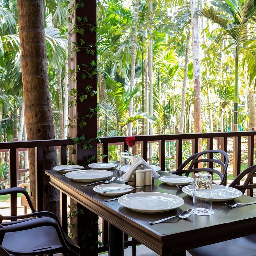 A dining table with plates and cutlery placed on it in an open air restaurant - Stone Wood Nature Resort, Gokarna