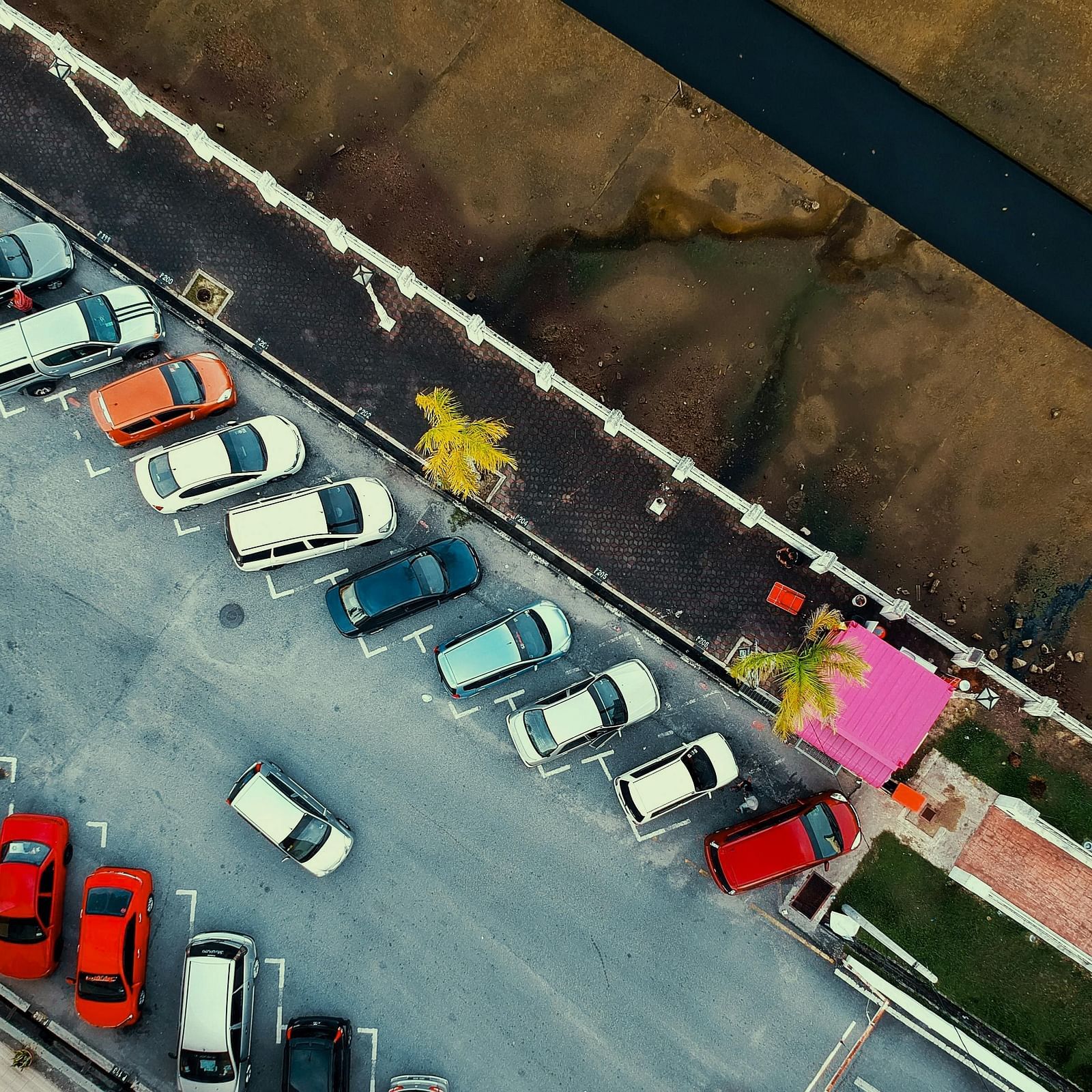 Aerial view of a parking lot with cars aligned next to a water canal