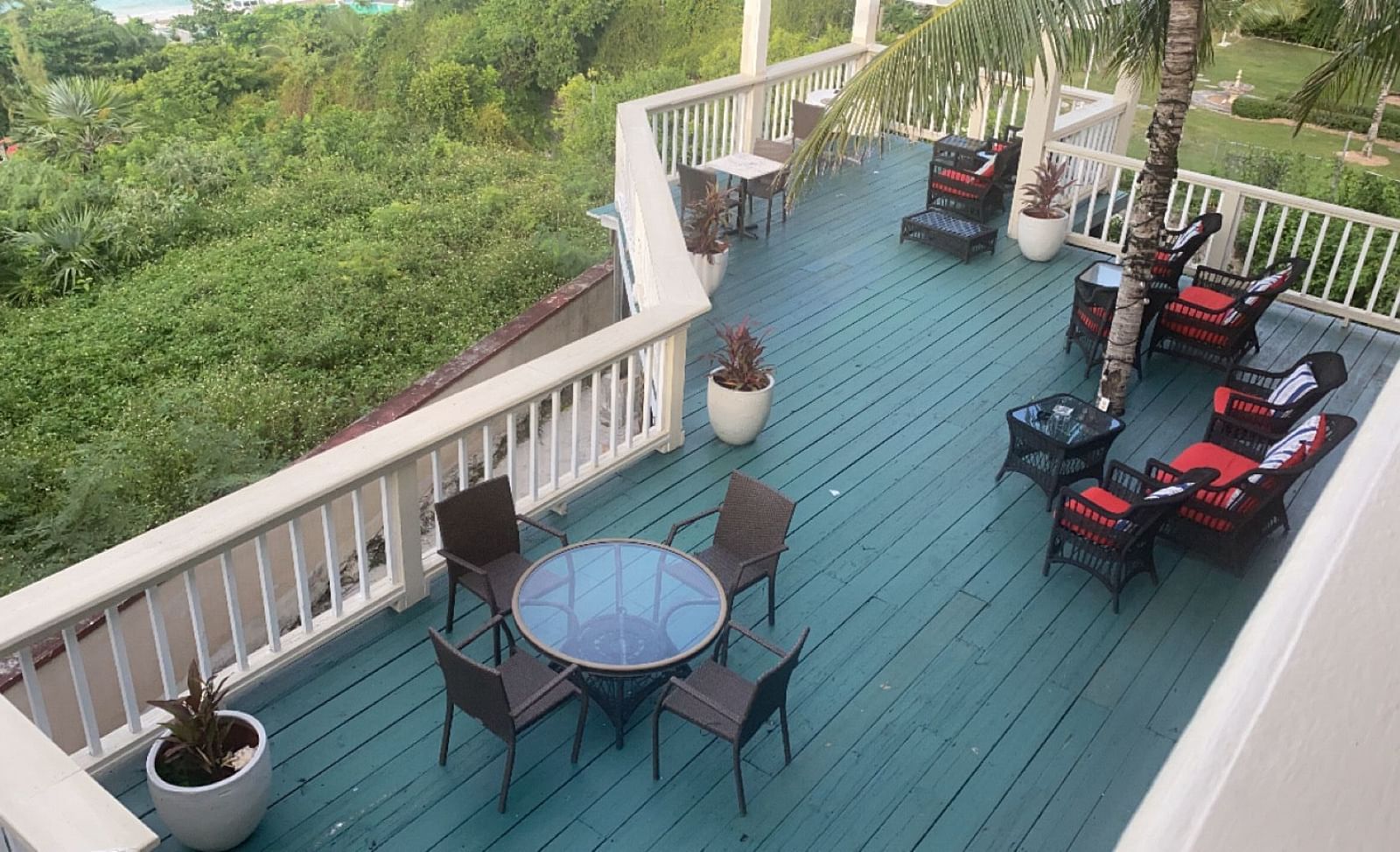 Elevated deck with chairs and tables overlooking lush greenery | A Stone's Throw Away