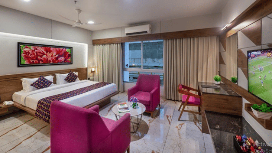 A room featuring a bed, a seating area with armchairs, and a television at Angel Lords Eco Inn Amreli.