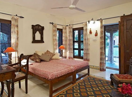An image of a room with a bed, bed side table, chairs, tables, lamps, ceiling fan and other decorative items - MANVAR Resort & Desert Camp