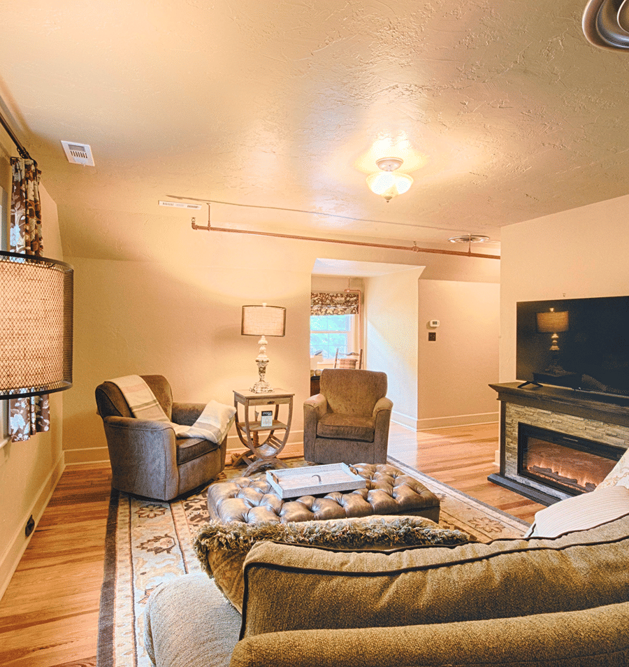 A cozy living room with a fireplace, seating area, and TV.