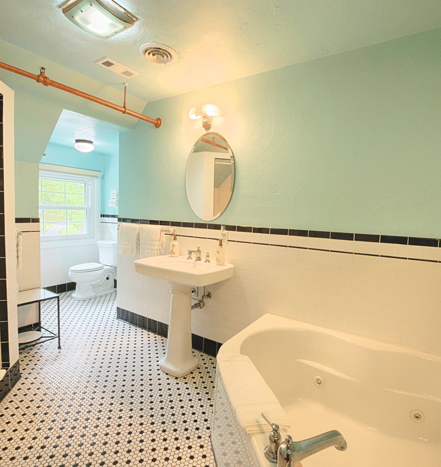A clean and well-lit bathroom with a clawfoot tub, pedestal sink, and tiled floor and walls.