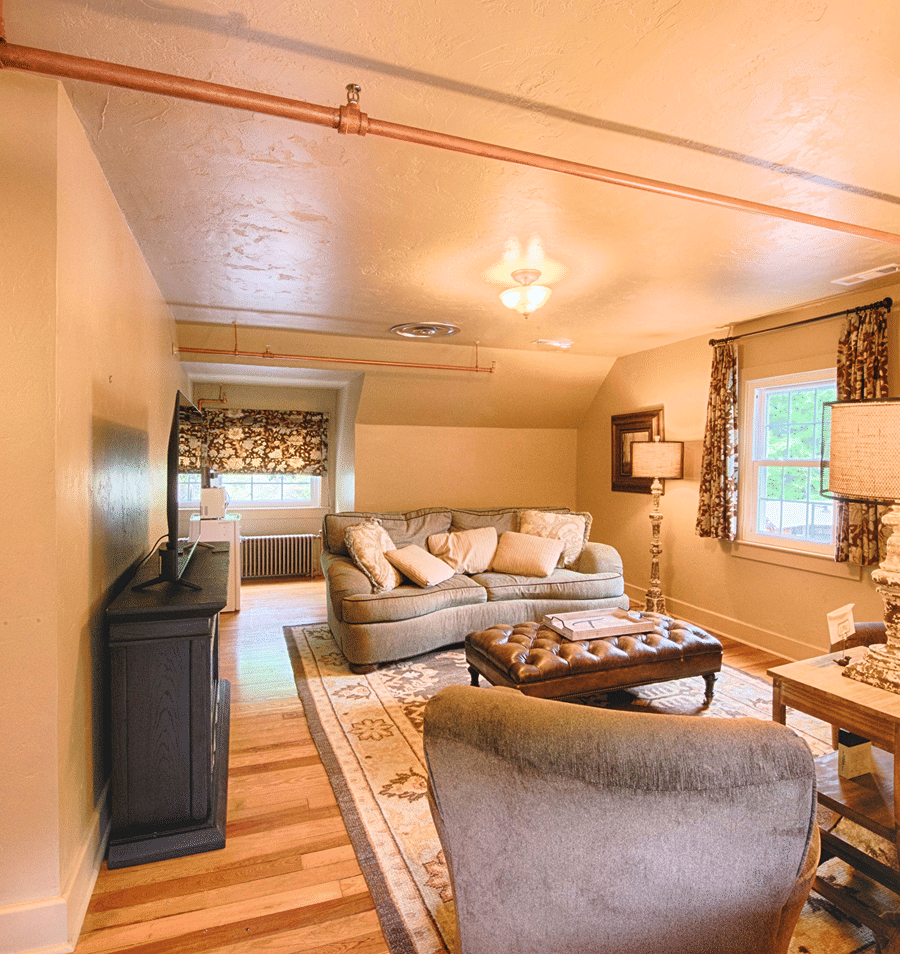 A wide view of a cozy living room with a sofa, armchair, coffee table, and TV.