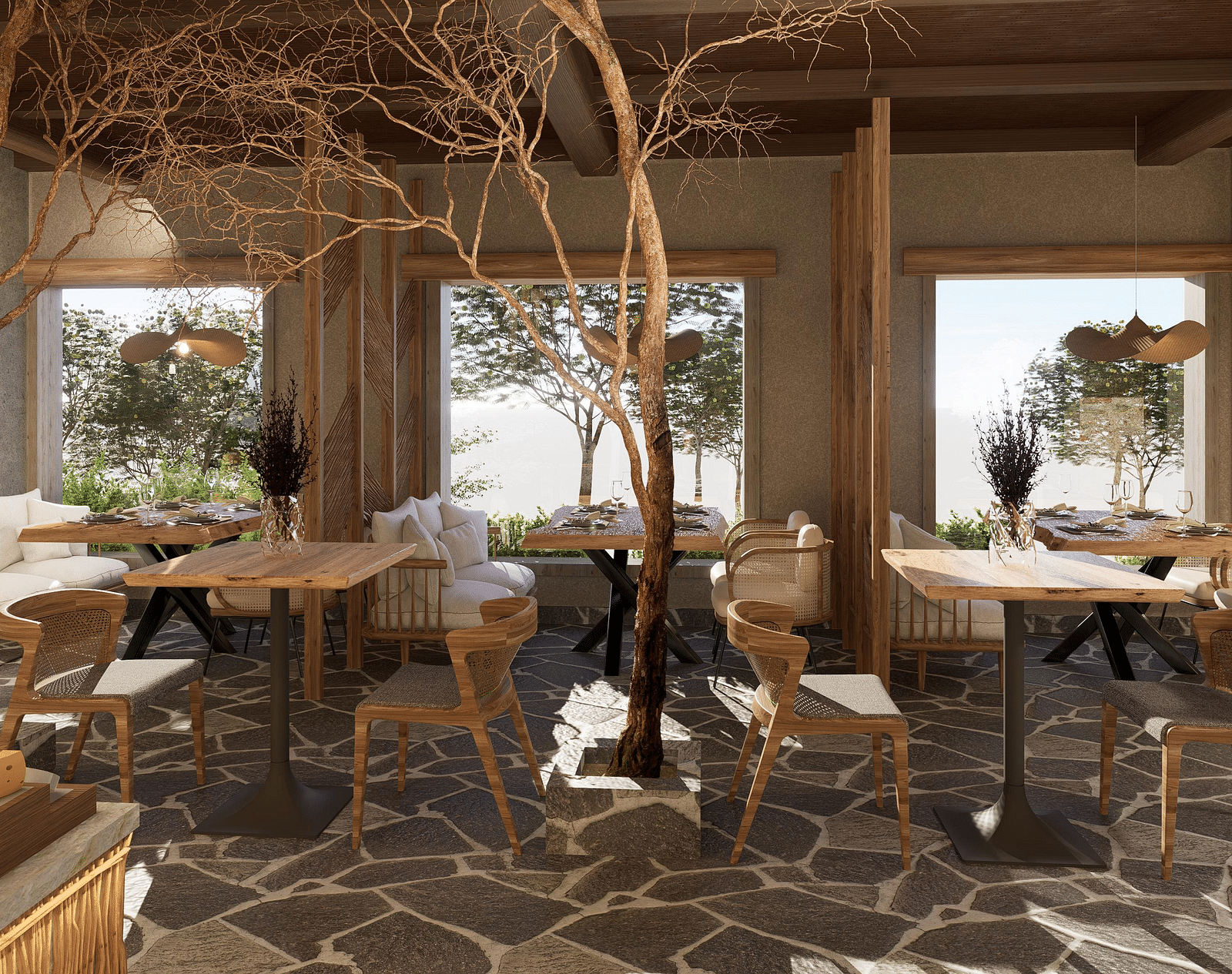 Side view of the restaurant at The Evren, Vagator, with arranged tables, chairs, and windows overlooking greenery.
