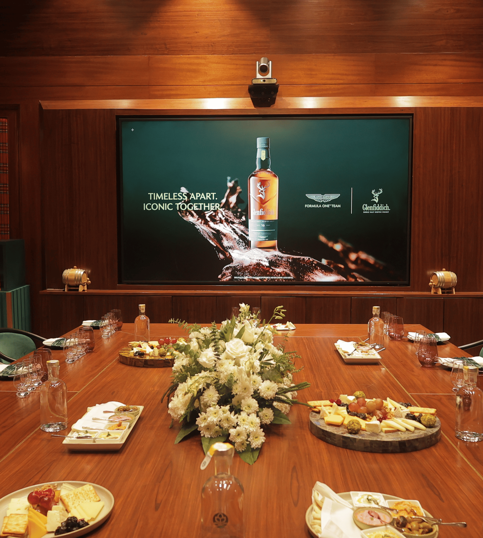 Long wooden dining table set with food platters and floral centerpieces in a wood-paneled private room at The Claridges New Delhi.