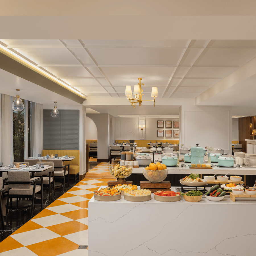 Modern living area with a grey sofa, yellow accent wall, and a large window overlooking a river and mountains.