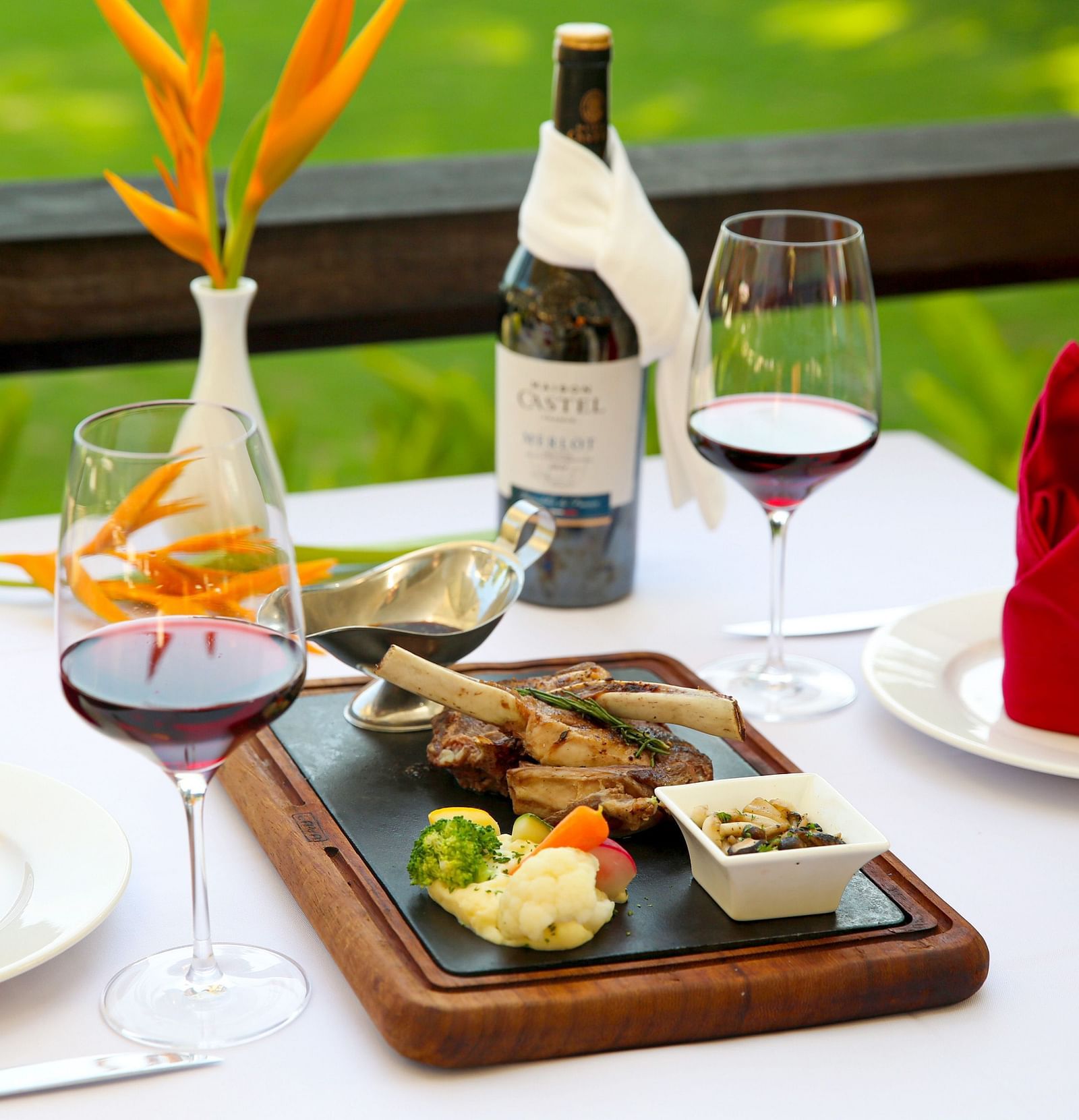 An image of a breakfast table where plates are decorated with towels beside a wine bottle and glass - Alibu Resort Nha Thrang