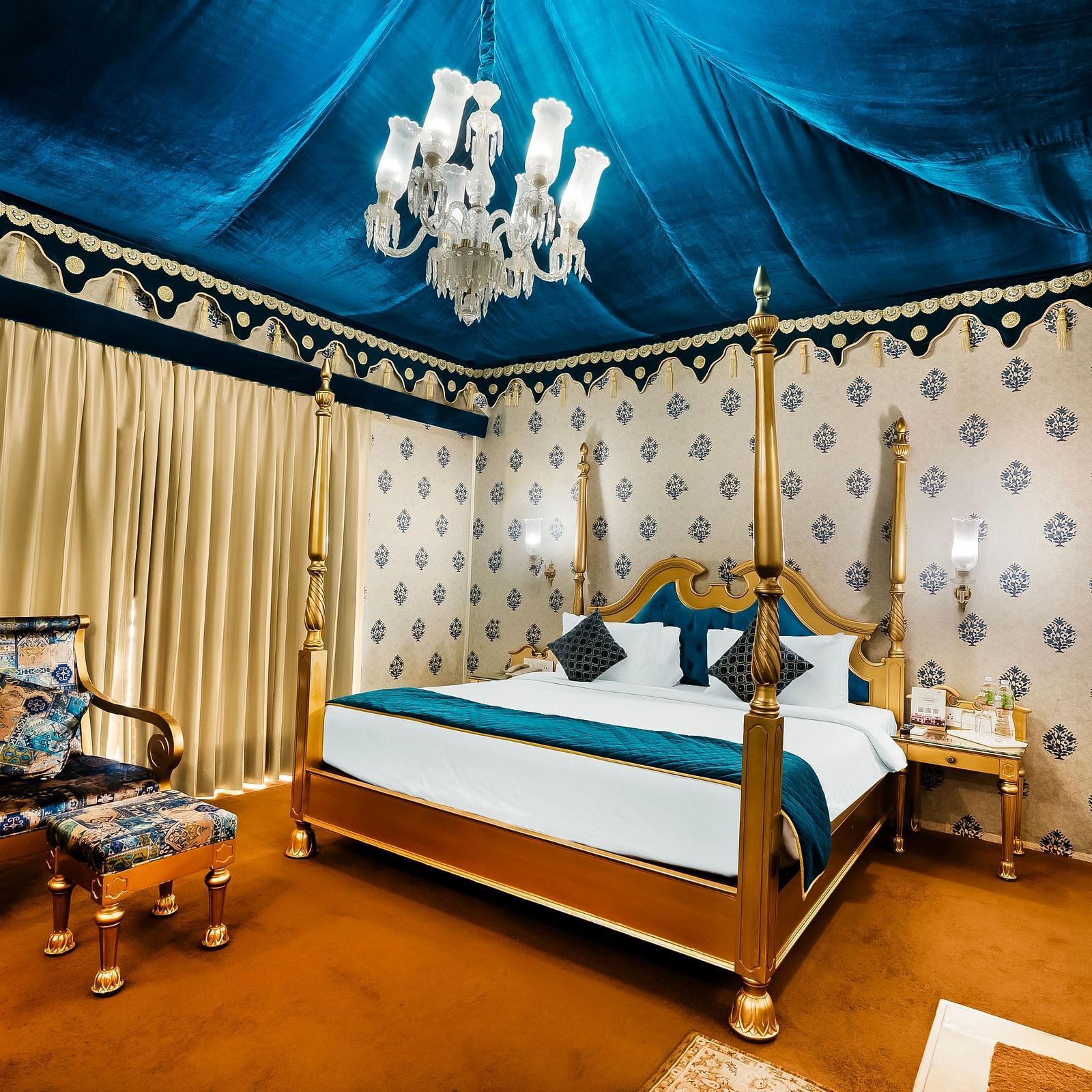 An overview of a tent with a double bed, a chair and a small table - Rajasthali Resort & Spa, Jaipur.