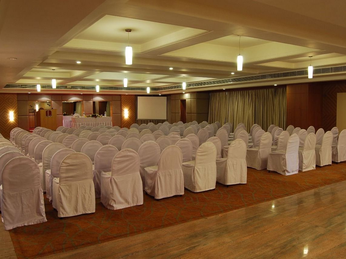 A well-lit banquet hall with neatly arranged chairs and elegant ceiling lights creating a warm ambience - Lords Plaza Ankleshwar