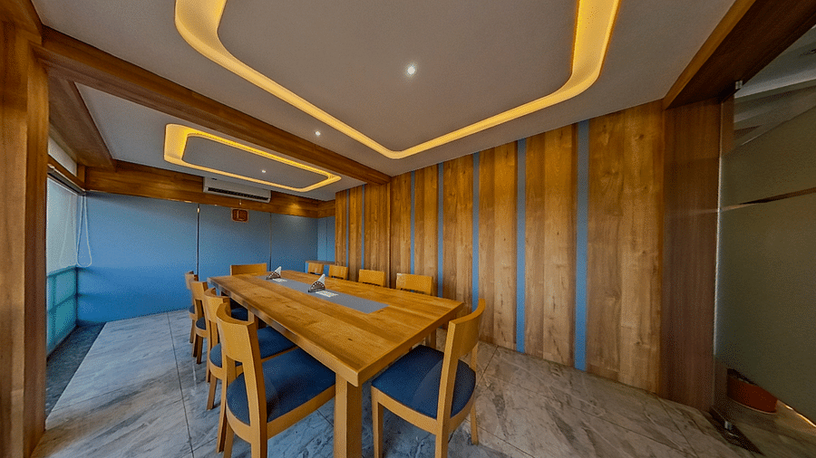 Elegant conference room at Lords Eco Inn Dahej with wooden paneling, blue upholstered chairs, and modern lighting for corporate meetings