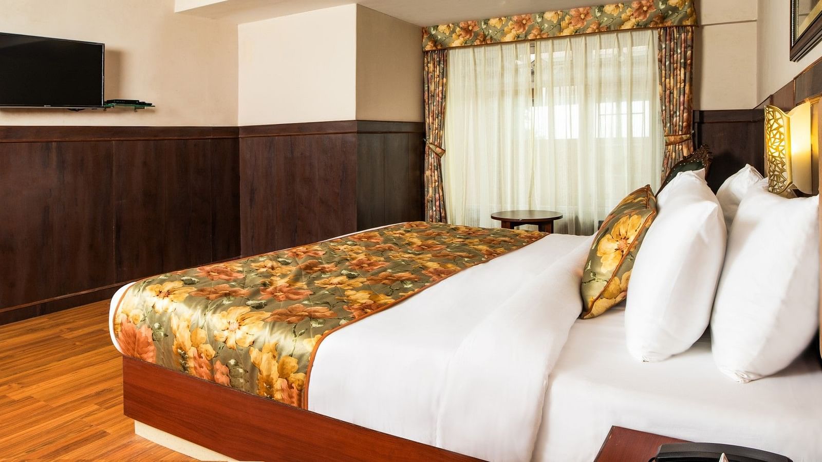 A side view of a bed in a room that has a glass window and TV on the wall | Summit Oakden Resort & Spa, Mall Road