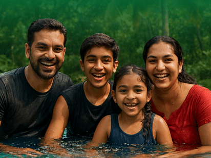Smiling family of four enjoying time together in a swimming pool surrounded by lush greenery.