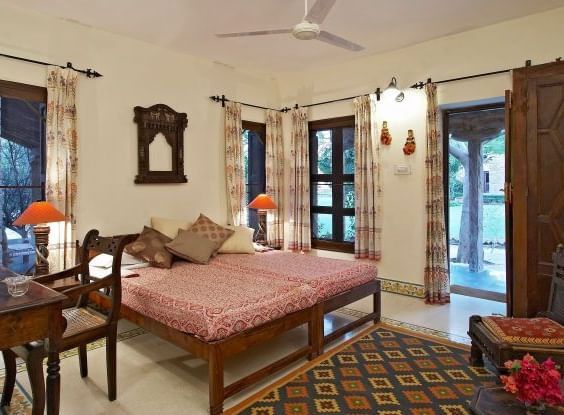 An image of a room with a bed, bed side table, chairs, tables, lamps, ceiling fan and other decorative items - MANVAR Resort & Desert Camp
