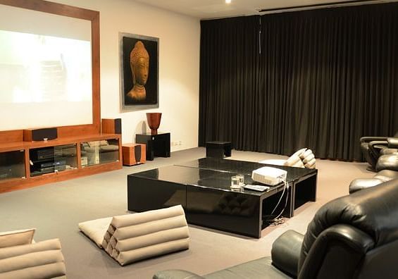 A modern home theatre with a large screen, dark drapes, and a minimalist design - Shreyas Retreat