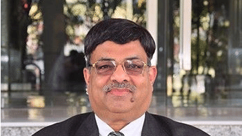 A man in a suit sitting and smiling for a professional photo, representing Lords Hotels & Resorts’ announcement of four new hotel signings in Gujarat.