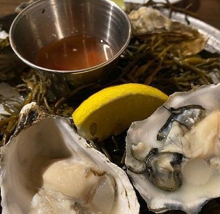 Fresh oysters on the half shell served with a mignonette sauce and lemon wedges.