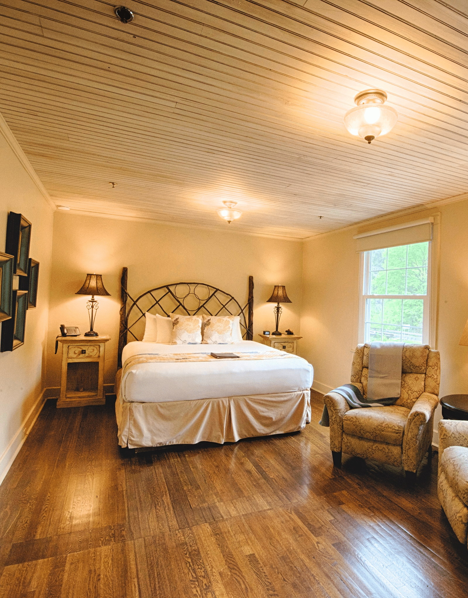 full view image of a room with wide windows featuring a cozy double bed and comfortable cushioned armchairs in front of it - Historic Tapoco Lodge
