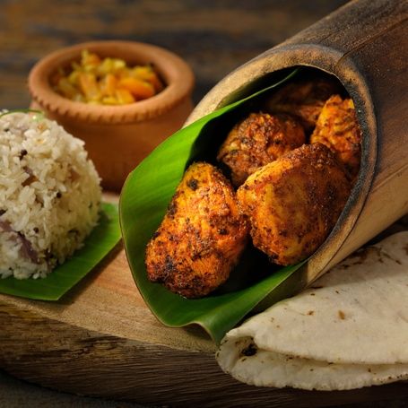 Bamboo chicken with rice and flatbread on a board.